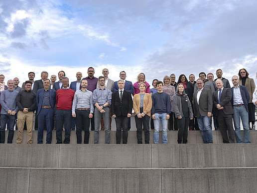Auf einer Dachterrasse stehen die Mitglieder des Erweiterten Senats in mehreren Reihen auf Steintreppen.